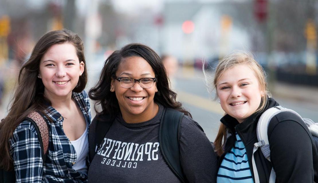 Three female students smiling as they walk to class.